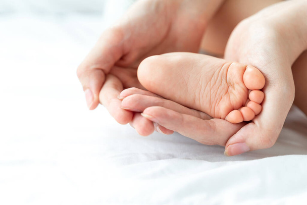 Newborn baby's feet are in the mother female hands  closeup - mom and baby concept - Photo, image