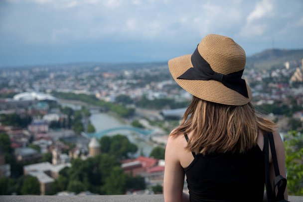 Şapkalı kadın Tiflis 'teki panoramadan bakıyor. - Fotoğraf, Görsel