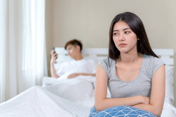Selectivo joven esposa sentada en la cama con sentirse aburrido acerca de su marido era adicto teléfono inteligente, concepto de pareja problemas - Foto, imagen