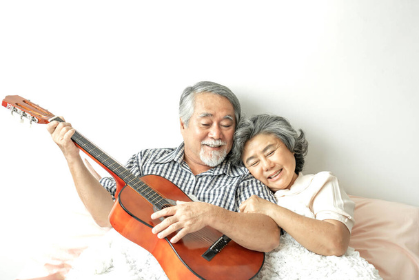 Happy love Starsza para uśmiech twarzy, Starszy para starzec i starsza kobieta relaks gry na gitarze akustycznej w łóżku - styl życia senior concept - Zdjęcie, obraz