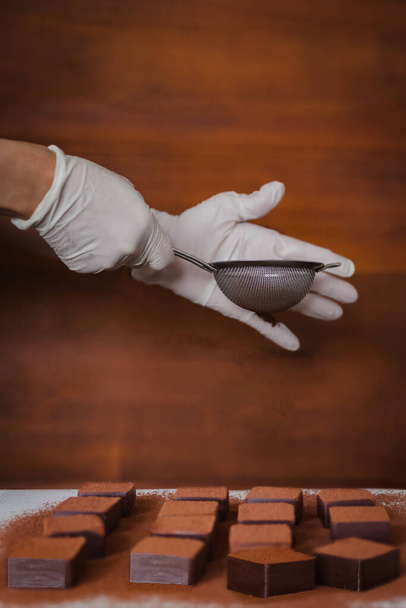 Жінка рука з рукавичкою додає какао порошок на свіжому шоколаді
. - Фото, зображення