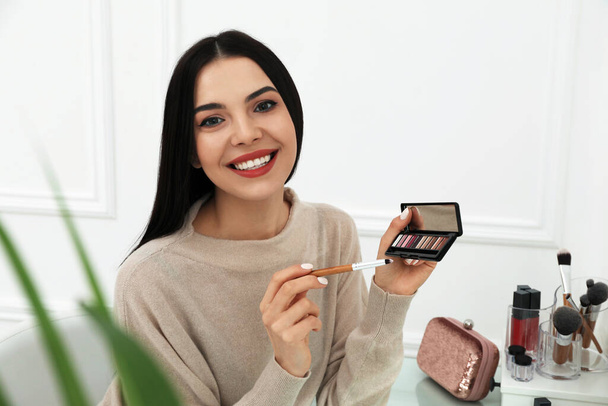 Beautiful happy woman applying makeup in room - Foto, imagen