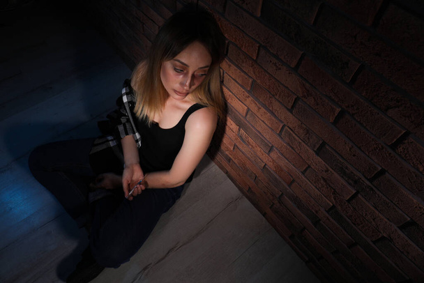 Overdosed drug addicted woman near brick wall. Space for text - Фото, зображення