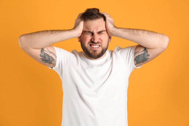 Man suffering from migraine on yellow background - Foto, afbeelding