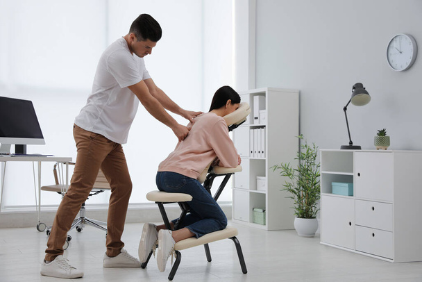 Woman receiving massage in modern chair indoors - Foto, afbeelding
