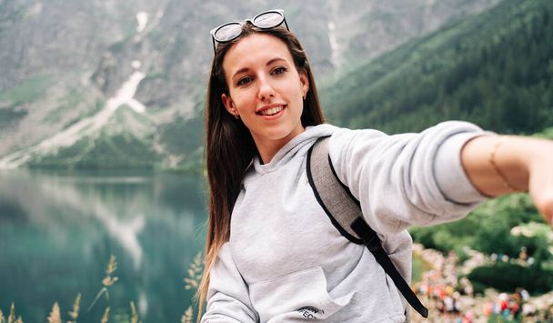 Une blogueuse. Jeune photographe de voyage avec smartphone sur fond de nature montagneuse estivale. Liberté, voyage d'été, concept de profession - Photo, image