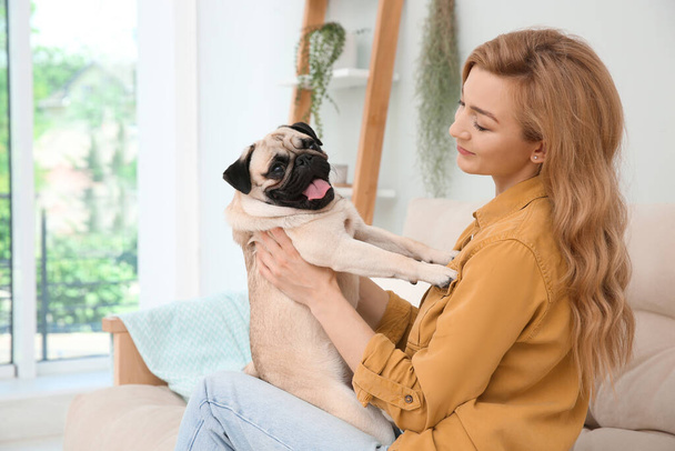 Woman with cute pug dog at home. Animal adoption - Foto, afbeelding