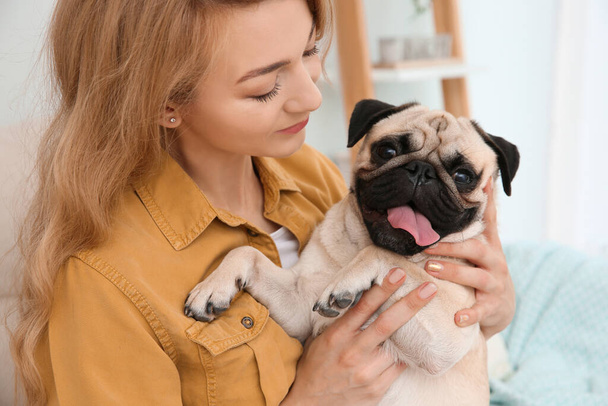 Woman with cute pug dog at home. Animal adoption - Zdjęcie, obraz