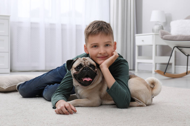 Boy with his cute pug on floor at home - Zdjęcie, obraz