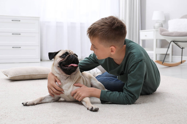 Boy with his cute pug on floor at home - Foto, afbeelding