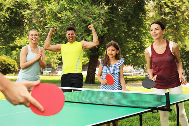 Happy family playing ping pong in park - Foto, imagen