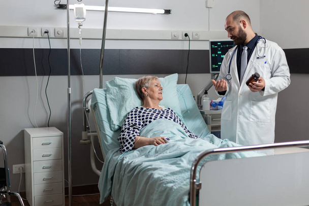 Enfermera paciente mayor acostada en cama de hospital - Foto, Imagen