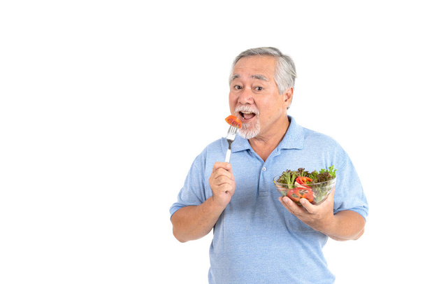 ライフスタイルシニアの男性は幸せな食事を楽しむ白い背景に隔離された新鮮なサラダ - 写真・画像