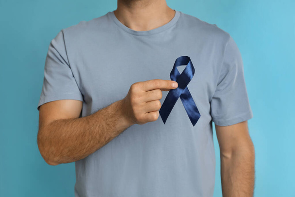 Man with ribbon on light blue background, closeup. Urology cancer awareness - 写真・画像