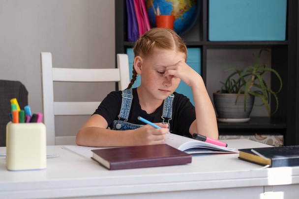 unavená zrzavá holka dělá domácí úkoly. Zpátky do školy. - Fotografie, Obrázek