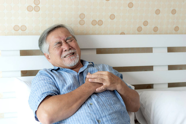 Senior mannelijke Aziatische lijden aan slechte pijn in zijn borst hartaanval thuis - senior hart-en vaatziekten - Foto, afbeelding