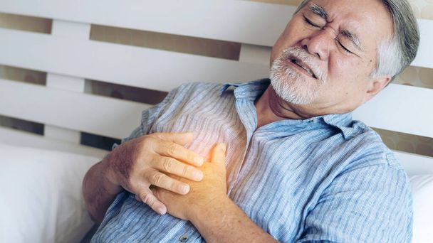 Senior mannelijke Aziatische lijden aan slechte pijn in zijn borst hartaanval thuis - senior hart-en vaatziekten - Foto, afbeelding