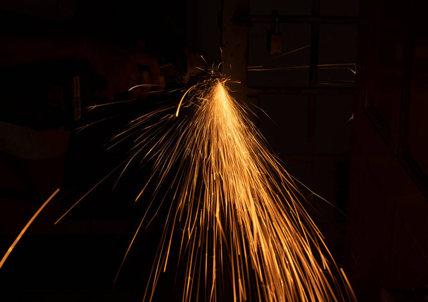Lähikuva kipinöitä leikkaamalla metallia sähkösahalla. Valikoivia painopisteitä. Hämärtynyt tausta - Valokuva, kuva