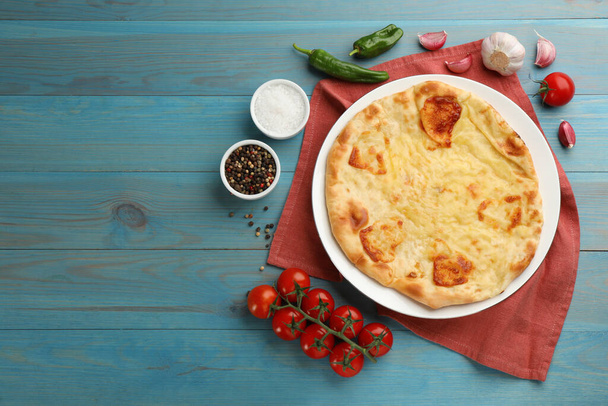 Delicious khachapuri with cheese on light blue wooden table, flat lay. Space for text - Foto, Imagem