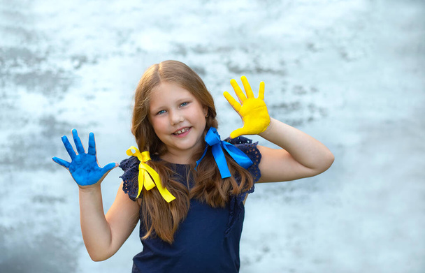 Sarı ve mavi renkli el falı gösteren mutlu bir kız. Bağımsızlık, bayrak. Ukrayna 'nın anayasa günü. Eğitim, okul, sanat ve resim konsepti - Fotoğraf, Görsel