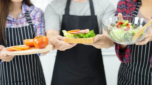 Cierra las manos haciendo sándwiches y verduras de ensalada para el desayuno, sandwichera en la cocina  - Foto, imagen
