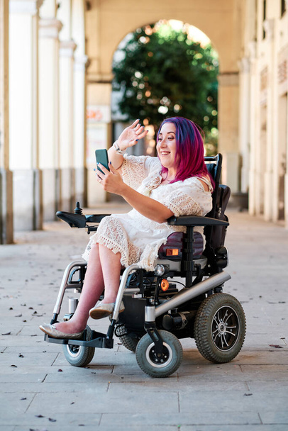 woman in wheelchair using smartphone for videoconference - streaming - Foto, afbeelding