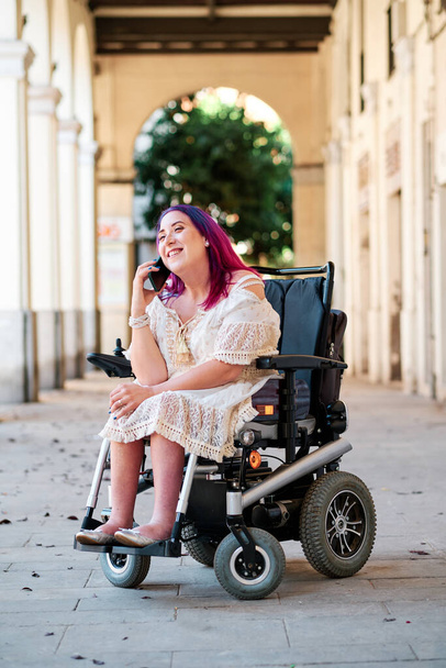 fogyatékkal élő nő tolószékben, okostelefont használva - Fotó, kép