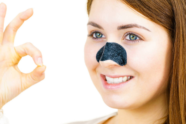 Woman appying clear-up strips on nose, using pore cleansing textile mask for blackheads. Girl taking care of skin complexion. Beauty treatment. Skincare. - Foto, Imagen