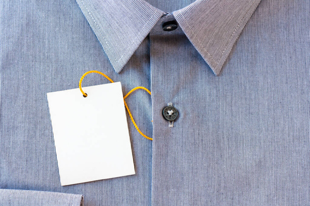 Μικρές γκρι ρίγες ανδρικό πουκάμισο με μια ετικέτα τιμή και κίτρινο-πορτοκαλί tag κορδόνι - Φωτογραφία, εικόνα