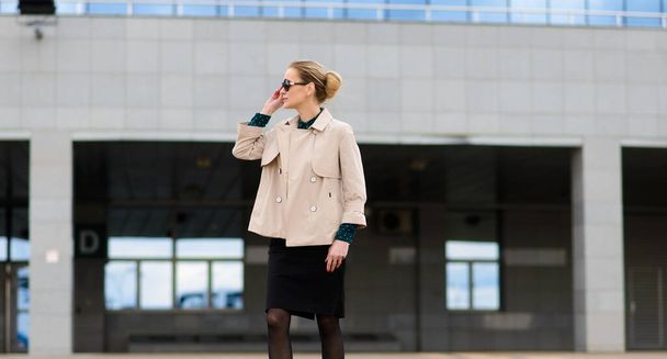Young beautiful businesswoman with sunglasses, phone, laptop, cup of coffee in the city street - Foto, Imagen
