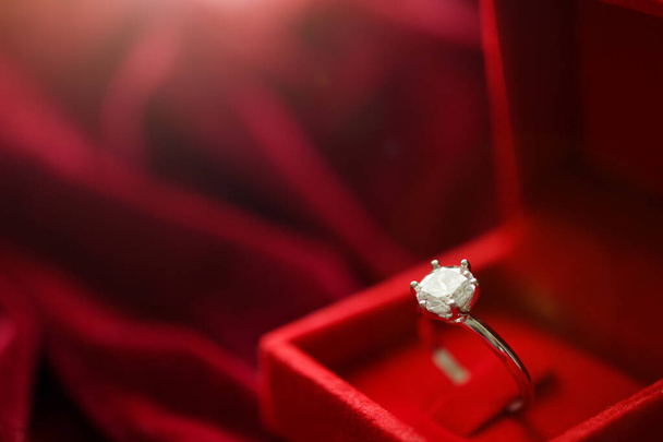 Kırmızı kumaş arka planda mücevher hediye kutusunda elmas yüzük. - Fotoğraf, Görsel