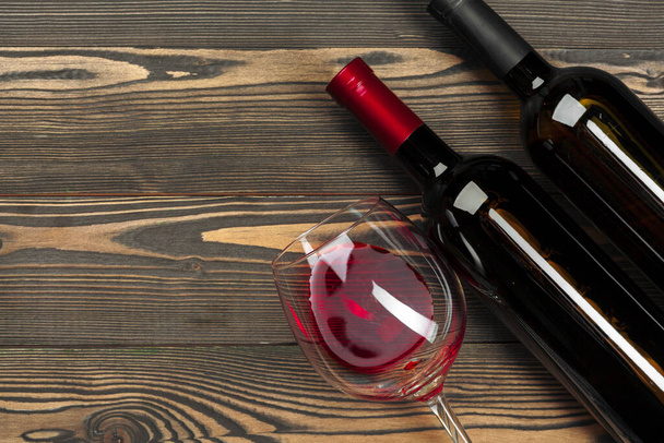glass and bottle with red wine on wooden background, top view - Foto, immagini