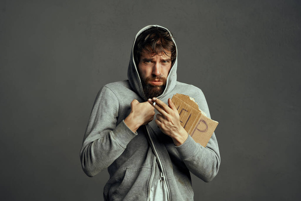 bebaarde dakloze man met een teken hulp  - Foto, afbeelding