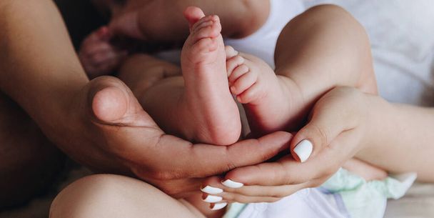 Mother and father holding baby feet in their hands - Foto, Bild