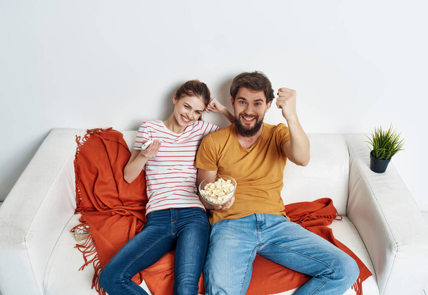 молода пара сидить на дивані попкорн дивитися сім'ю у відпустці
 - Фото, зображення