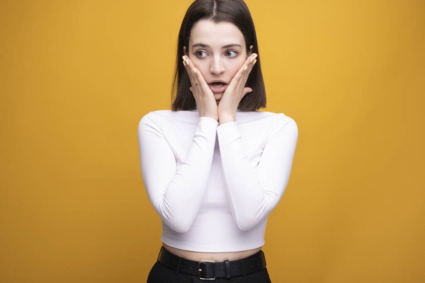 Excited screaming young woman standing against isolated yellow background - Photo, Image