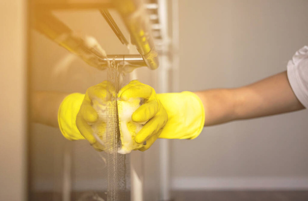 Hand in rubber glove washes the stove door in home kitchen, housework concept background  - Φωτογραφία, εικόνα