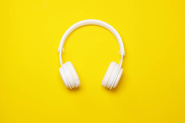 Moderní bílé bezdrátové sluchátka na žlutém pozadí, trendy minimální styl. - Fotografie, Obrázek