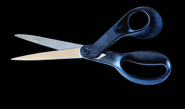 Scissors with black plastic handles for cutting paper and thin materials on a black background - Фото, зображення