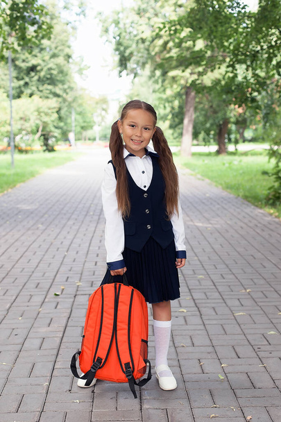 Το έξυπνο είναι υπέροχο.. πίσω στο σχολείο. παιδί με στολή κουβαλάει σχολική τσάντα. έννοια της εκπαίδευσης. ανάπτυξη της παιδικής ηλικίας. Το χαρούμενο κορίτσι έχει χαριτωμένο χαμόγελο. ευτυχισμένη προνήπιο κορίτσι με σακίδιο στην αυλή του σχολείου. - Φωτογραφία, εικόνα
