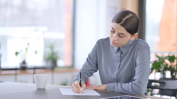 Latin Woman Writing on Paper in Office  - Photo, Image