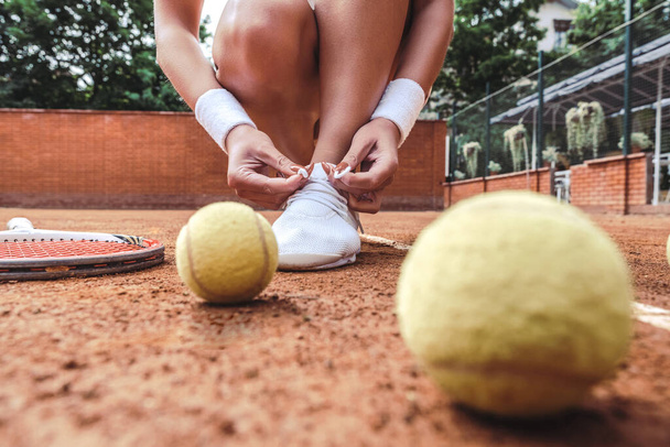 Close up view of Tennis player tying shoelaces in tennis court. Young woman on tennis court in the sport club. - Photo, Image