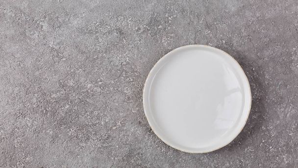 Empty white plate on gray concrete background, closeup - Фото, изображение