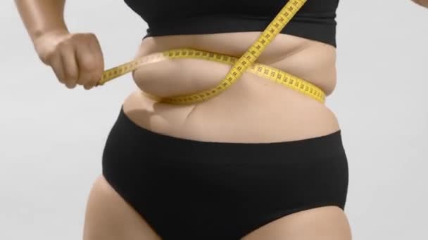 Liikalihavuusongelmia. Lihava nainen mittaa teippiä vyötärön ympäriltä. Silti ampui laadukkaita video. - Materiaali, video