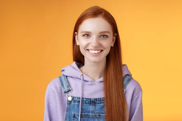 Attractive modern hipster young redhead girl smiling delighted relaxed talking have casual joyful day downtown walking friends wearing purple hoodie overalls, summer vibes, standing orange wall - Fotografie, Obrázek