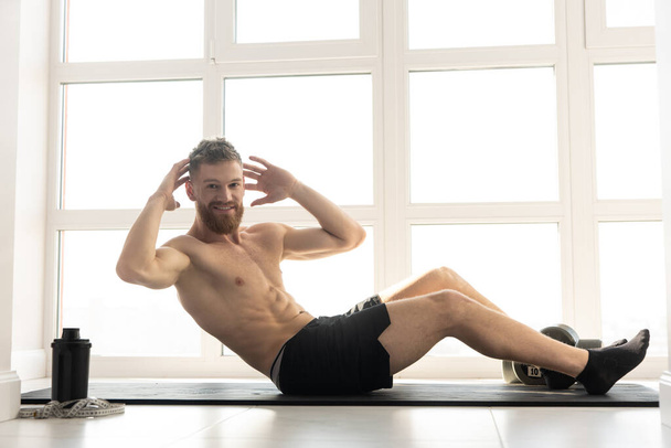 European sportsman doing crunching on fitness mat - Foto, afbeelding