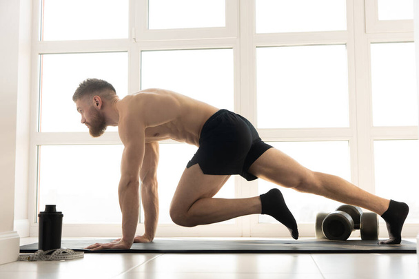 Ευρωπαίος αθλητής που ασκεί σωματική άσκηση σε στρώμα γυμναστικής - Φωτογραφία, εικόνα