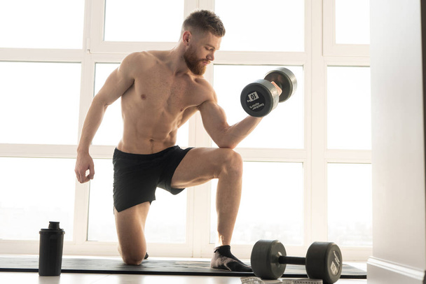 Αθλητής κάνει άσκηση με αλτήρα για fitness mat - Φωτογραφία, εικόνα