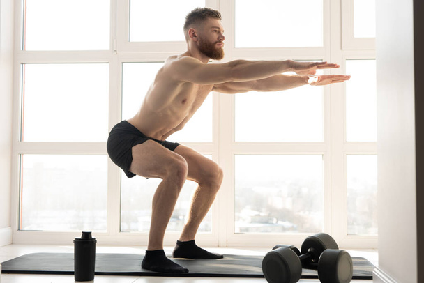 European sportsman sit ups on fitness mat - Фото, изображение