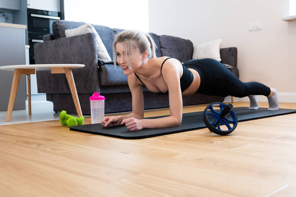 Sportswoman doing plank on fitness mat at home - Photo, Image
